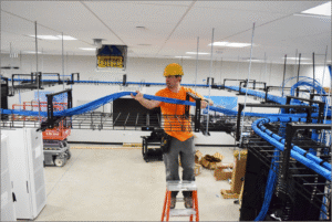 Instalator układający wiązki kablowe.  Praca instalatora podczas układania kabli i okablowania strukturalnego.